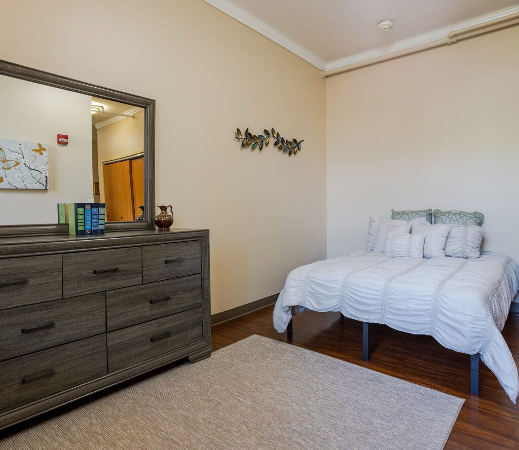 A bedroom with an armoire and a bed at Celebrate Senior Living.